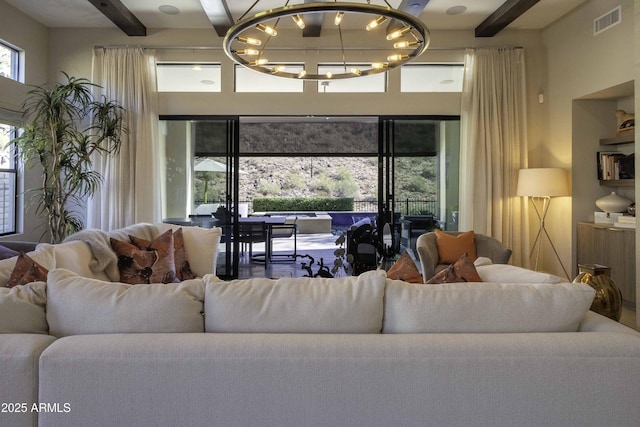 living room featuring beamed ceiling and an inviting chandelier