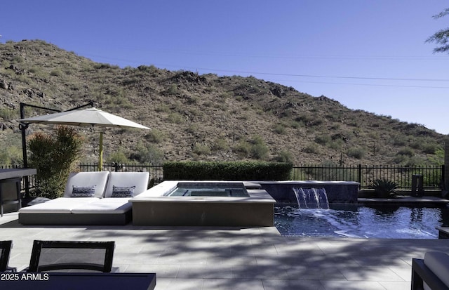 exterior space featuring an outdoor living space, an in ground hot tub, pool water feature, and a mountain view