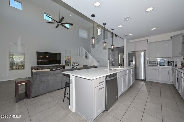 kitchen with sink, a kitchen island with sink, a kitchen breakfast bar, black appliances, and decorative light fixtures