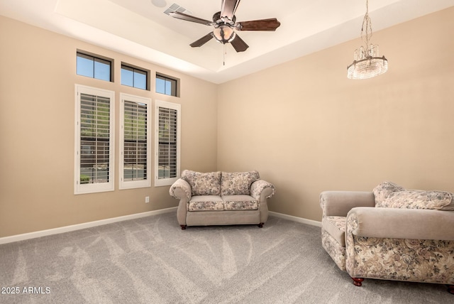 living area with a raised ceiling, carpet, and baseboards