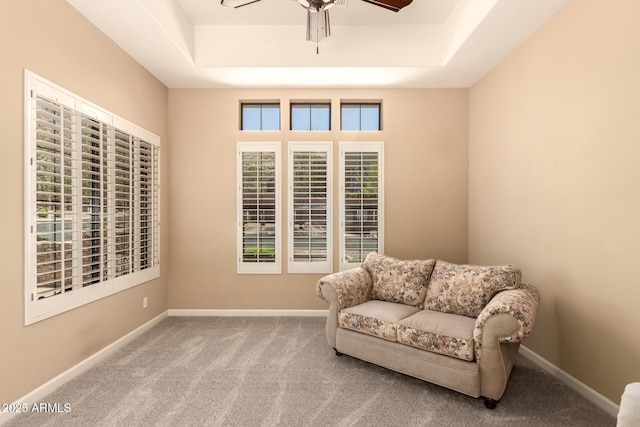 sitting room featuring a raised ceiling, a ceiling fan, carpet, and baseboards