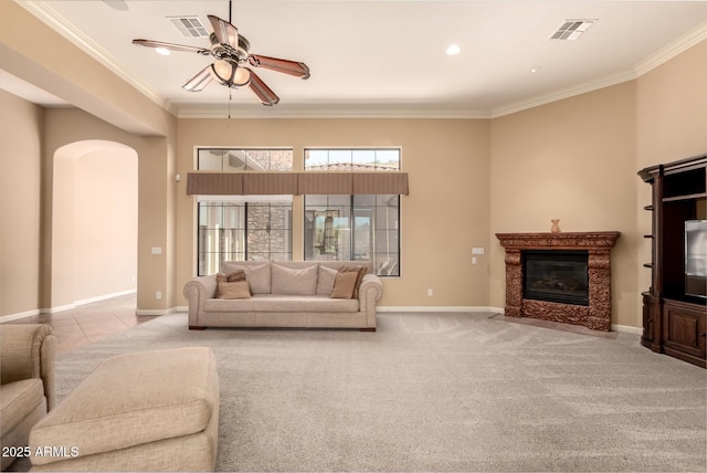 living room with arched walkways, ceiling fan, crown molding, a high end fireplace, and carpet flooring