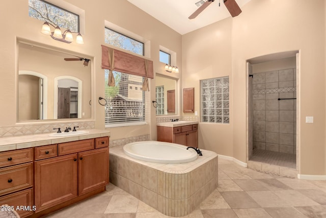 bathroom featuring ceiling fan, a bath, a tile shower, a towering ceiling, and tile patterned floors