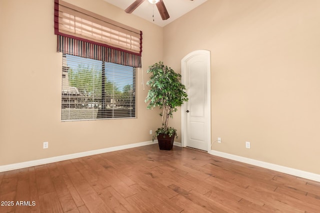 unfurnished room featuring wood finished floors, ceiling fan, baseboards, and lofted ceiling