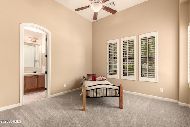 bedroom with light carpet, ensuite bathroom, and baseboards