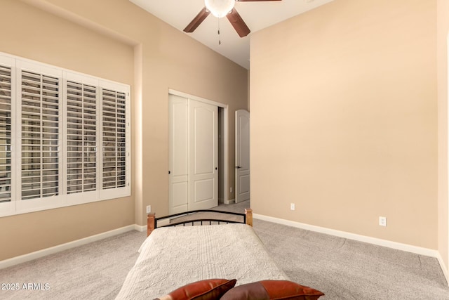 carpeted bedroom with a closet, baseboards, and a ceiling fan