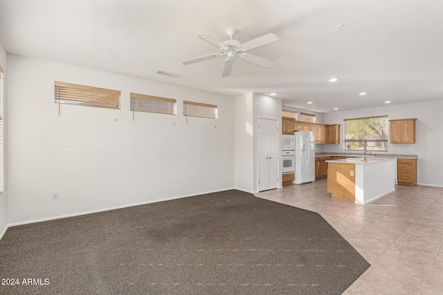 kitchen with sink, white appliances, a center island, light tile patterned floors, and ceiling fan