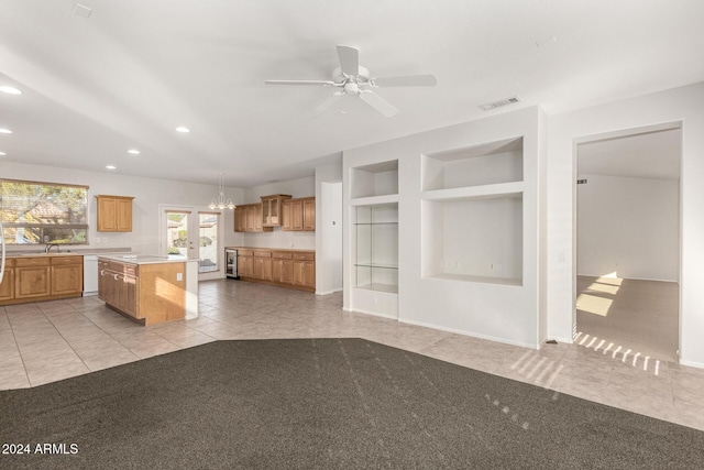 kitchen with a kitchen island, built in features, dishwasher, hanging light fixtures, and light tile patterned floors