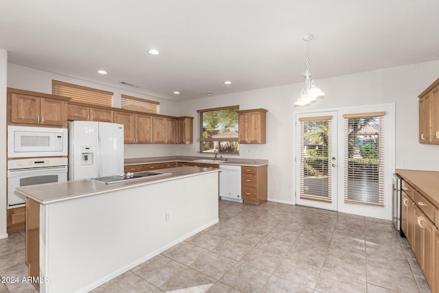 kitchen with pendant lighting, sink, white appliances, a kitchen island, and french doors