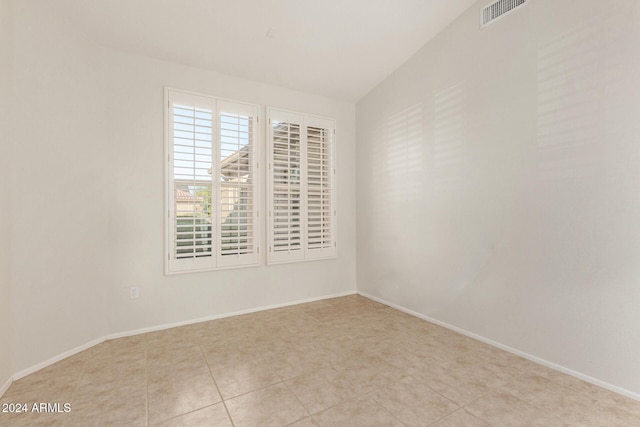 spare room with light tile patterned flooring and vaulted ceiling