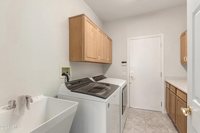 laundry room featuring sink, light tile patterned floors, cabinets, and washing machine and clothes dryer