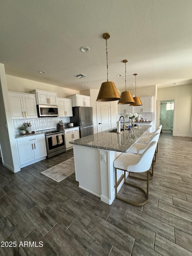 4173 W 27th Ln, Yuma, AZ 85364 - kitchen with appliances with stainless steel finishes, white cabinets, backsplash, an island with sink, and wood tiled floors