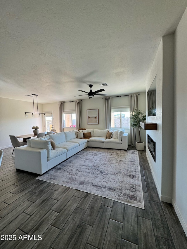 4173 W 27th Ln, Yuma, AZ 85364 - living room with dark wood-style flooring, a textured ceiling, ceiling fan, and a large fireplace