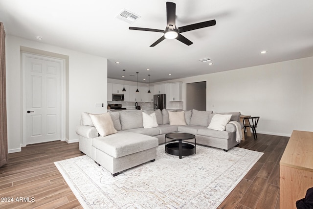 living room featuring ceiling fan and dark hardwood / wood-style floors