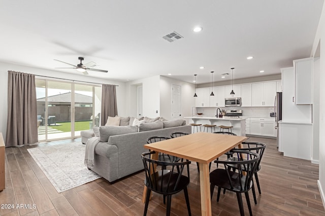 dining area featuring ceiling fan, sink, and dark wood-type flooring