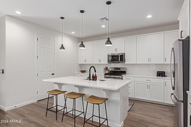 kitchen featuring hardwood / wood-style floors, white cabinetry, an island with sink, and appliances with stainless steel finishes