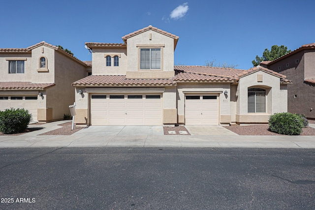 mediterranean / spanish house with a tile roof, driveway, an attached garage, and stucco siding