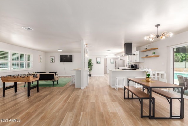 dining room with light wood-style floors, a chandelier, and baseboards