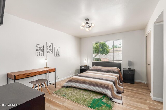 bedroom featuring a chandelier, light wood-style floors, and baseboards