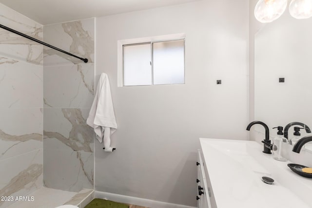 full bath featuring a marble finish shower and vanity