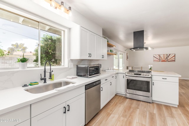kitchen with stainless steel appliances, island range hood, a sink, a peninsula, and open shelves