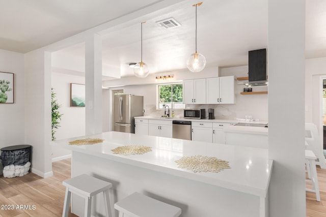 kitchen with stainless steel appliances, light wood-type flooring, a sink, and a breakfast bar area