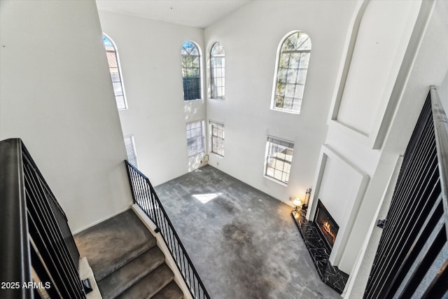 carpeted entrance foyer with a high end fireplace and a high ceiling