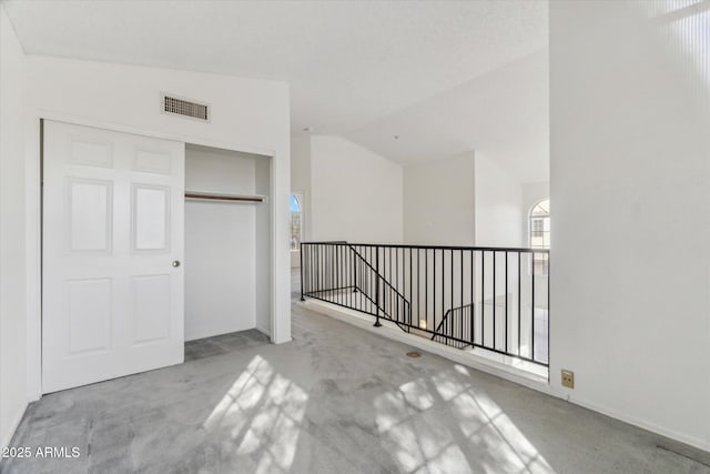 corridor featuring vaulted ceiling and light carpet