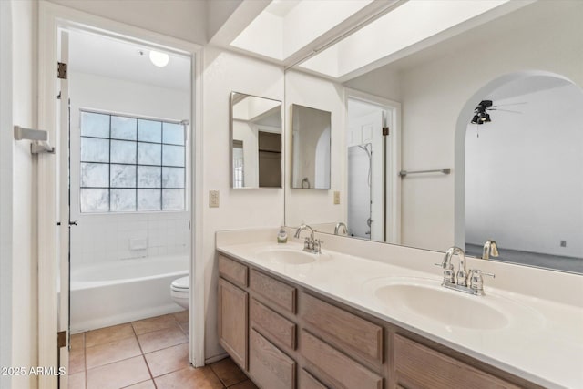 full bathroom with tile patterned flooring, vanity, tiled shower / bath combo, ceiling fan, and toilet