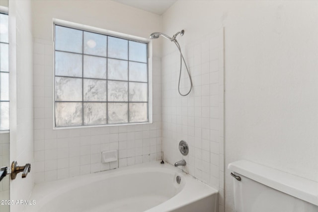 bathroom featuring tiled shower / bath, a healthy amount of sunlight, and toilet