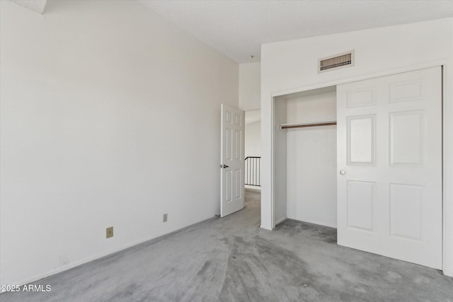 unfurnished bedroom with lofted ceiling, light carpet, and a closet