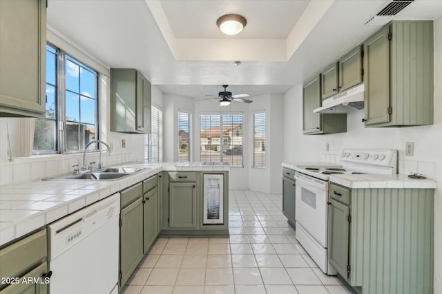 kitchen with sink, white appliances, green cabinets, tile counters, and light tile patterned flooring