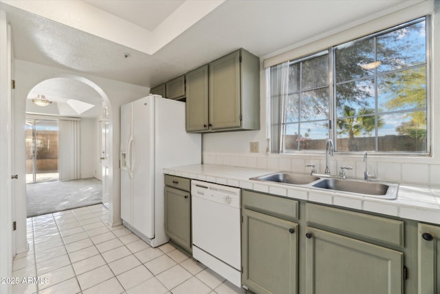 kitchen featuring light tile patterned flooring, sink, tile counters, green cabinets, and white appliances