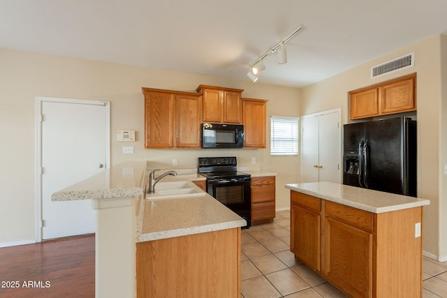 4010 W Fremont Rd, Phoenix, AZ 85041 - kitchen featuring black appliances, a sink, a peninsula, rail lighting, and brown cabinets
