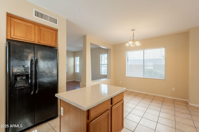 4010 W Fremont Rd, Phoenix, AZ 85041 - kitchen with black fridge with ice dispenser, light tile patterned floors, a chandelier, a kitchen island, and baseboards