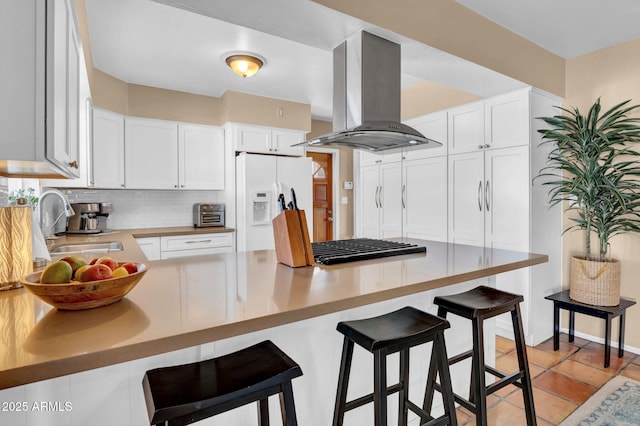 kitchen with a peninsula, island exhaust hood, a sink, white fridge with ice dispenser, and backsplash