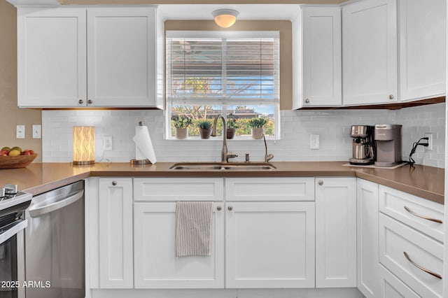 kitchen with a sink, tasteful backsplash, appliances with stainless steel finishes, and white cabinetry