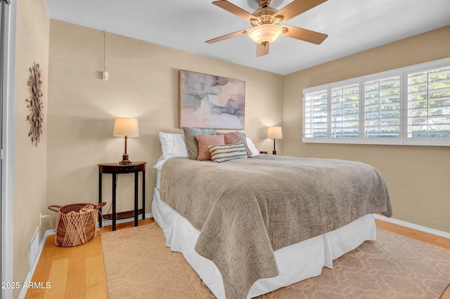 bedroom featuring baseboards, wood finished floors, and a ceiling fan