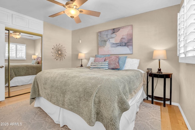 bedroom with a ceiling fan, light wood-style floors, a closet, and baseboards