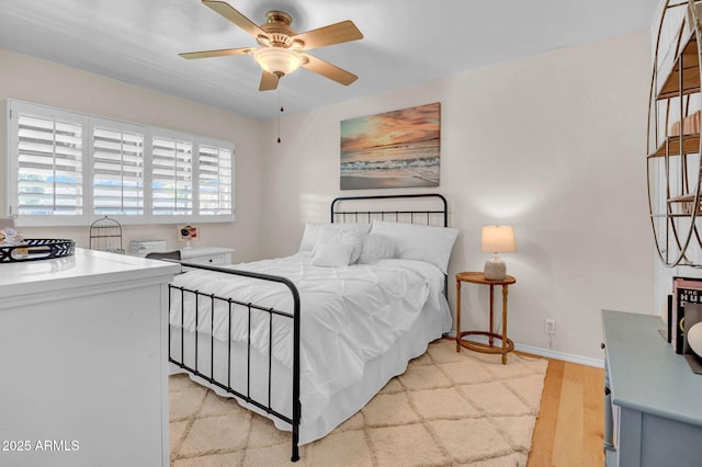 bedroom with light wood-style flooring, baseboards, and ceiling fan