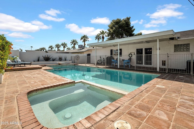 view of swimming pool featuring a pool with connected hot tub, fence, a diving board, ceiling fan, and a patio area