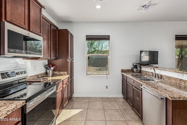 7090 S 252nd Dr, Buckeye, AZ 85326 - kitchen featuring stainless steel appliances, a sink, light stone counters, baseboards, and light tile patterned flooring