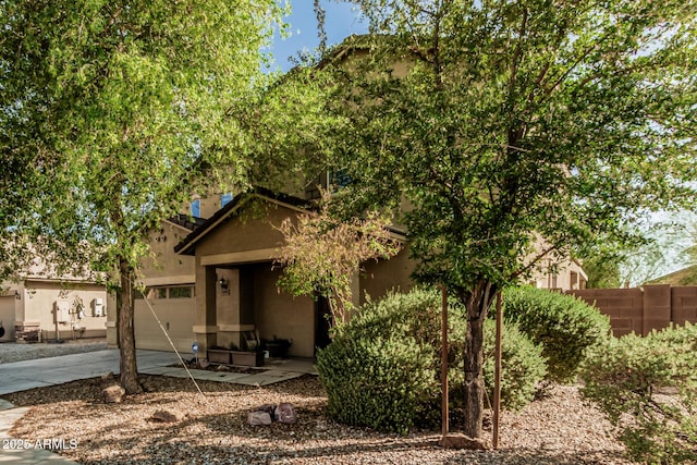 7090 S 252nd Dr, Buckeye, AZ 85326 - view of property hidden behind natural elements with concrete driveway, an attached garage, and stucco siding