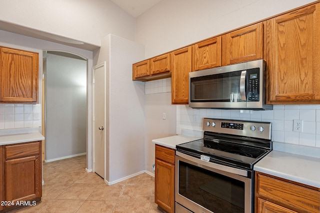 kitchen featuring backsplash, light tile patterned floors, and stainless steel appliances