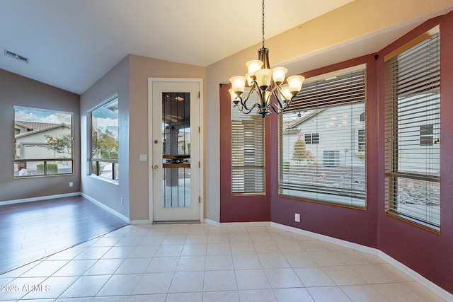 unfurnished dining area featuring lofted ceiling, light tile patterned floors, and a notable chandelier