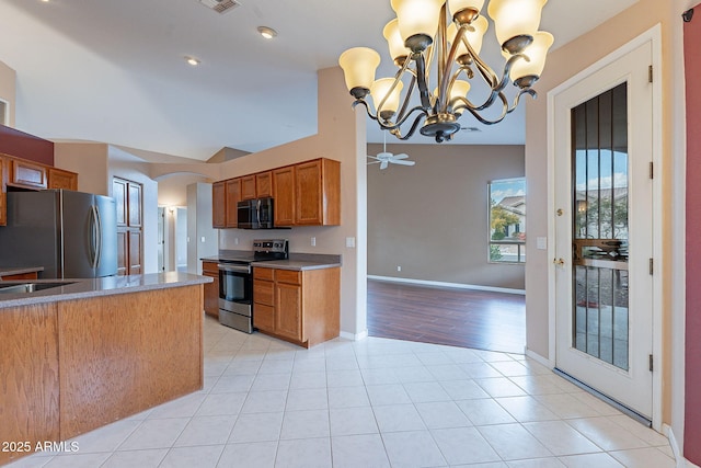 kitchen featuring lofted ceiling, decorative light fixtures, light tile patterned floors, stainless steel appliances, and ceiling fan with notable chandelier