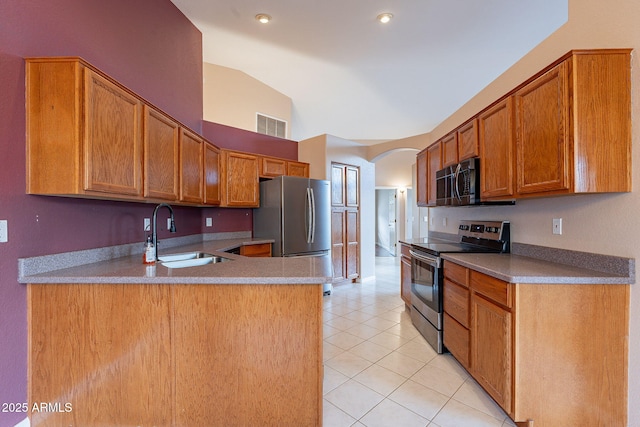 kitchen with vaulted ceiling, light tile patterned flooring, appliances with stainless steel finishes, sink, and kitchen peninsula