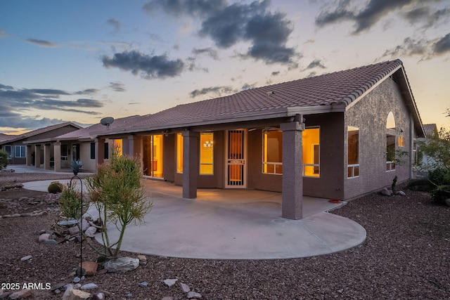 back house at dusk featuring a patio area