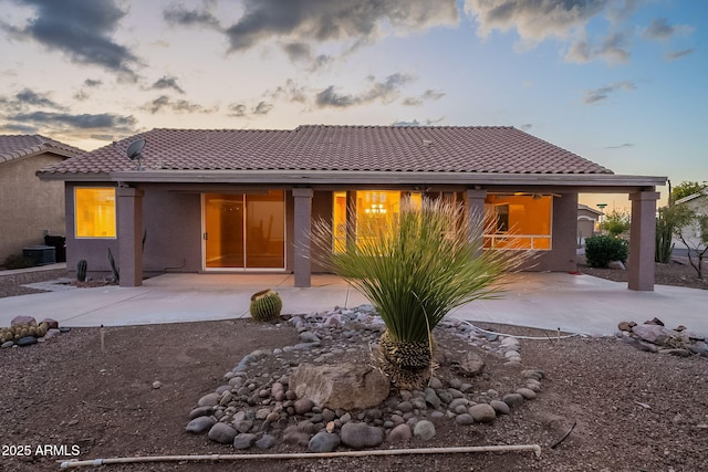 back house at dusk featuring a patio area