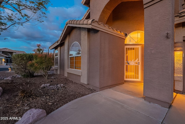 property exterior at dusk featuring a patio area